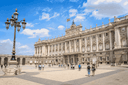 Royal Palace of Madrid exterior and courtyard on a sunny day with visitors exploring the historic landmark.